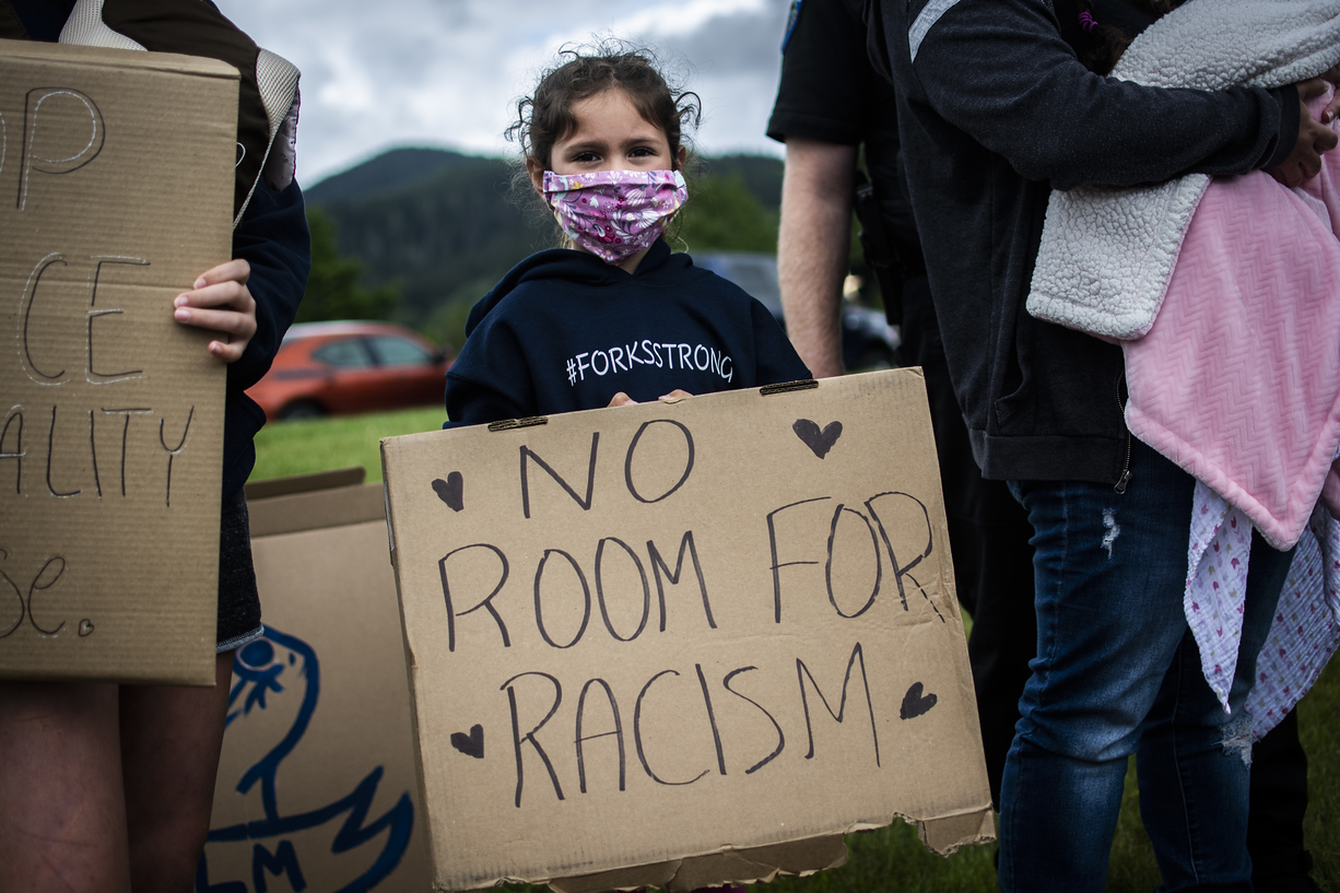 Young girl holding a sign reading "no room for racism"