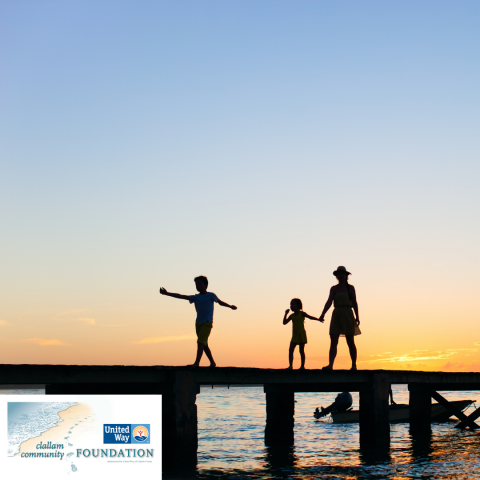 Silhouette of three people walking on a bridge over water at sunset