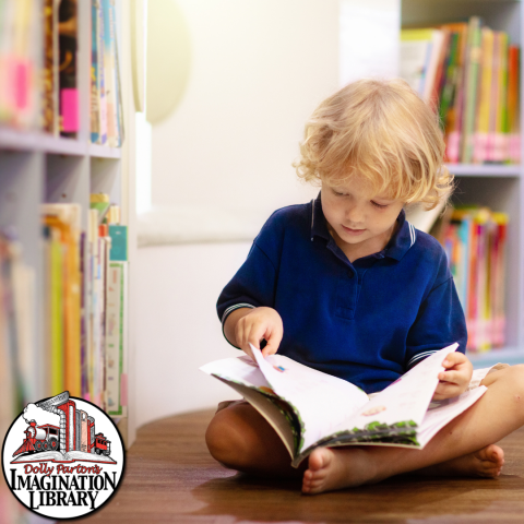 Young child sitting on floor reading a book