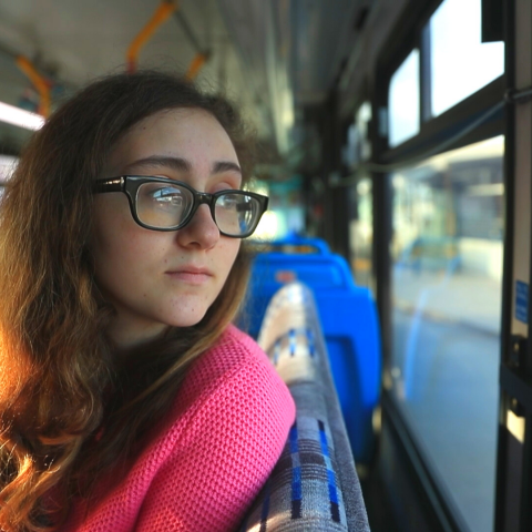 Teenager looking out the window of a bus