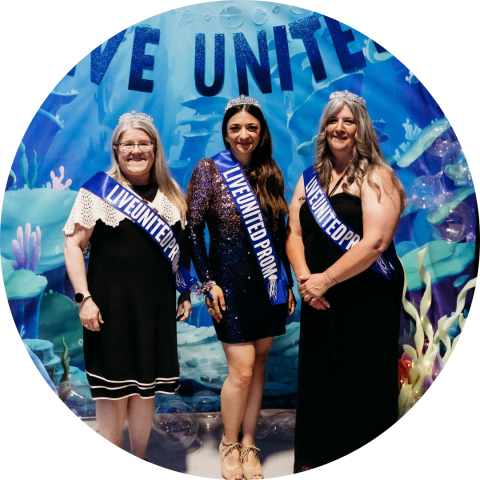 Three women in prom sashes and crowns in front of an under the sea backdrop