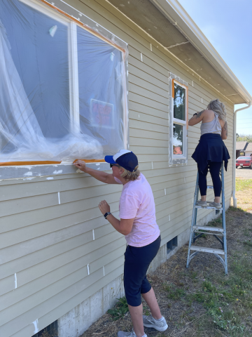 Two people prepping a house to be painted