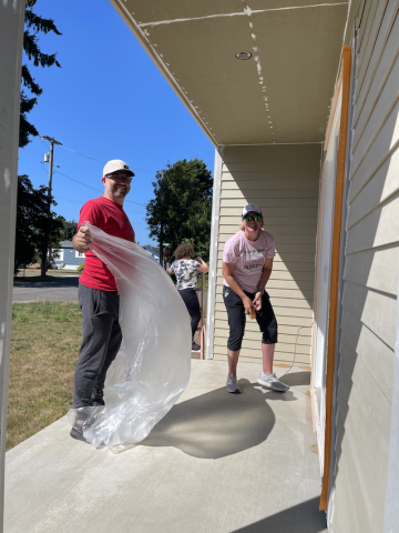 Two people smiling while prepping a house for paint