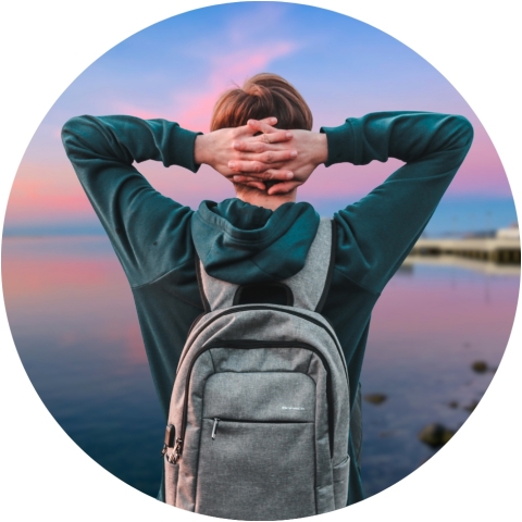 A teen boy wearing a backpack looks out at Port Angeles harbor