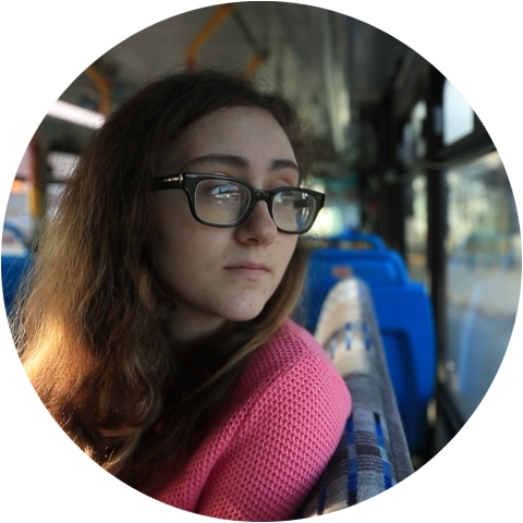 A young woman looking out the window of a bus