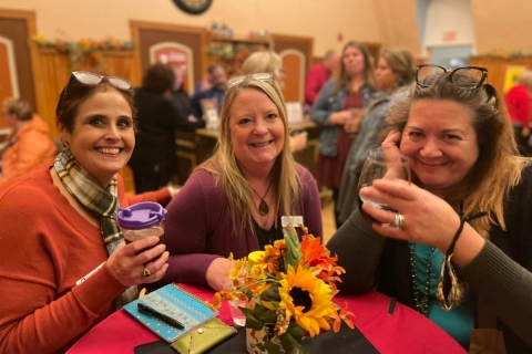 Three women at a table holding drinks