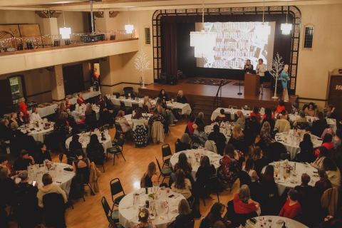 Two women on a stage speaker to a room full of people