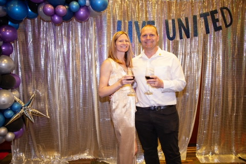 Smiling people in front of sparkly backdrop