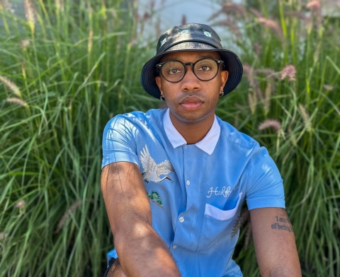 Photo of a man in a bucket hat and blue shirt among reeds