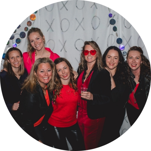 A group of smiling women wearing black and red