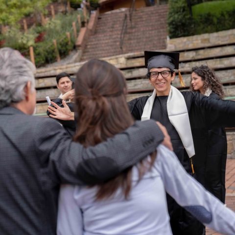 graduate in cap and gown running to hug his parents