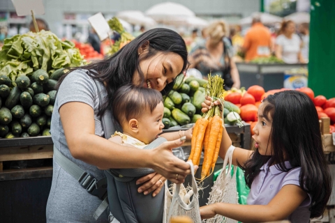 a women grocery shopping with two young children
