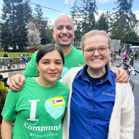Three smiling people standing together outside