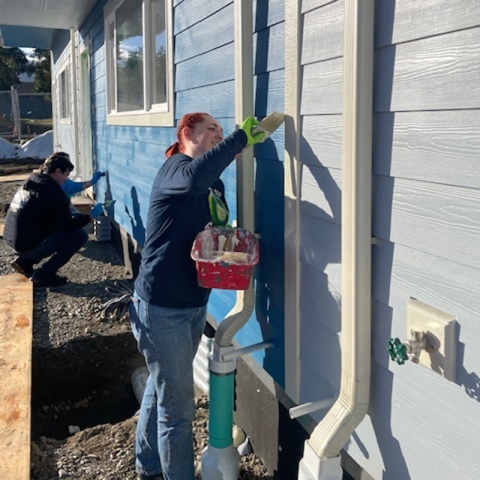 2 people painting the outside of a house