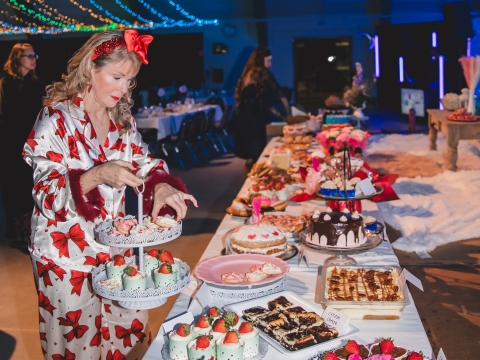 Woman in red and white pajamas placing desserts on a dessert table