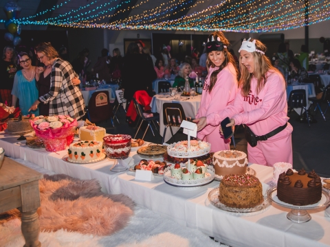 women in pajamas perusing a table covered in desserts