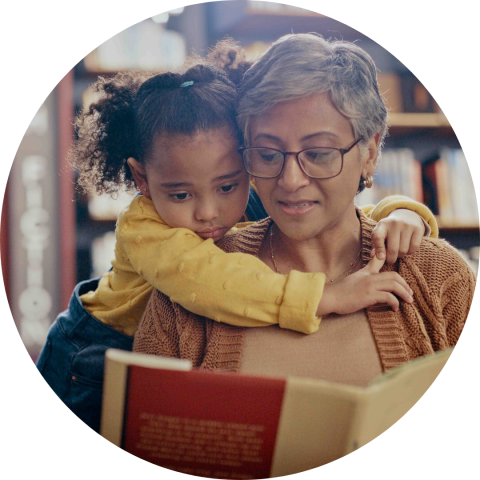 grey haired woman reading to child in a library
