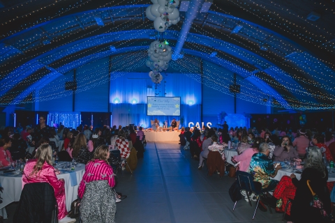 gym decorated for an evening event full of round tabled and filled with blue light