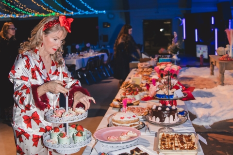 a woman standing at a table full of desserts