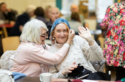 two elderly women smiling and waving at the camera