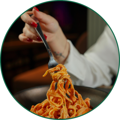 a hand holding a fork with pasta curled around it
