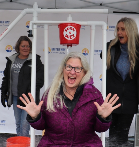 three women gathered around a bucket dunk contraption