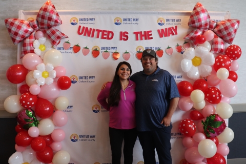 smiling couple in front of balloon covered backdrop
