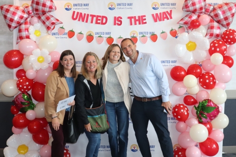 smiling people in front of balloon covered backdrop