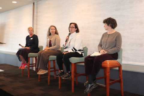 4 women sitting on high chairs speaking with a microphone