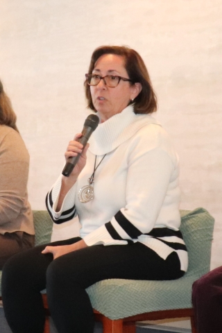 woman on stage speaking into microphone