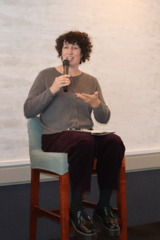 woman on stage speaking into microphone