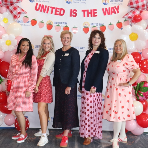 5 smiling women in front of a balloon covered backdrop