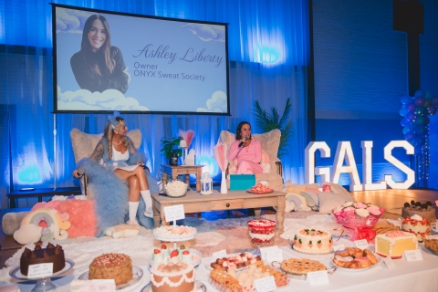 A table of desserts in front of two women  in armchairs on a stage