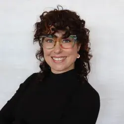 headshot of woman with curly hair in black turtleneck